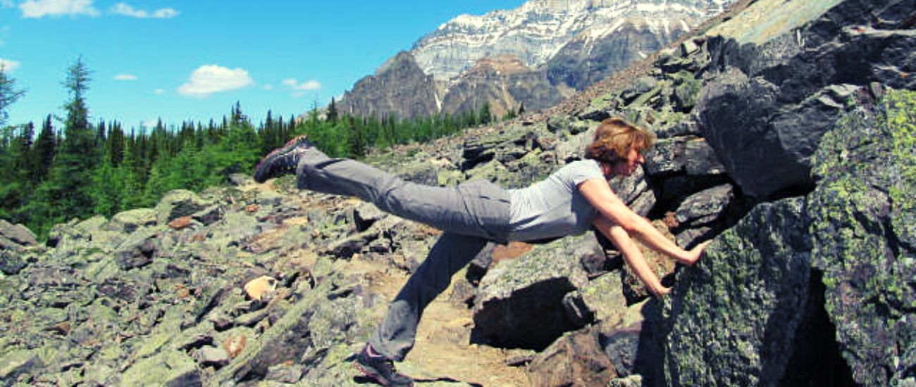 woman does plank on hike in mountains to stretch while walking